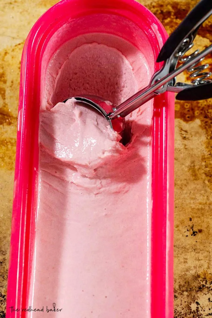 A scoop running through a container of cranberry amaretto ice cream