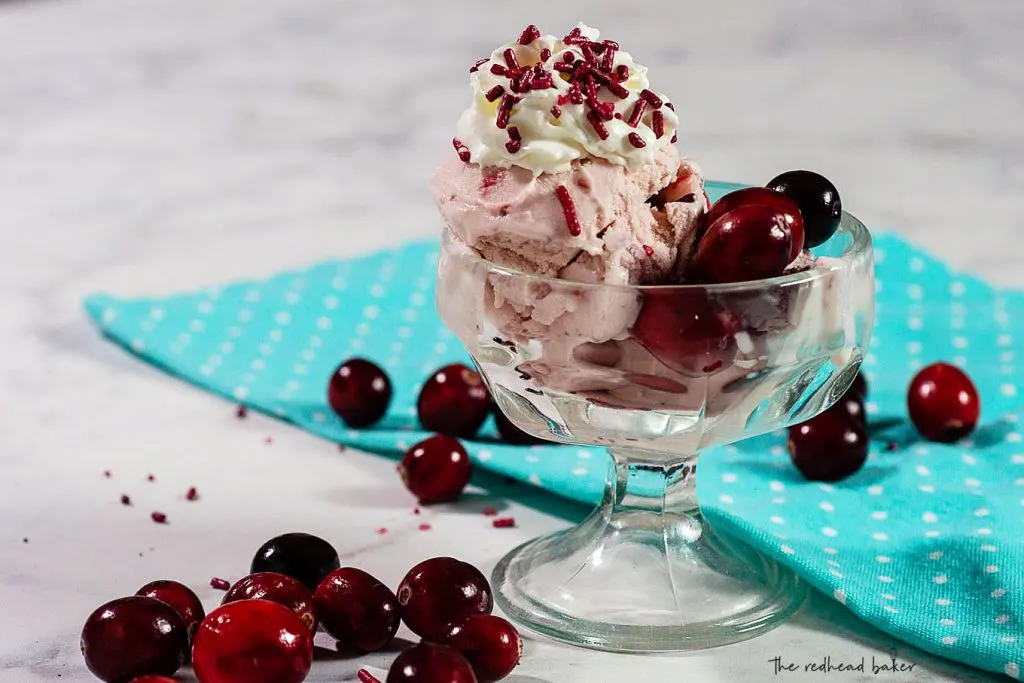 A dish of cranberry amaretto ice cream with whipped cream and sprinkles