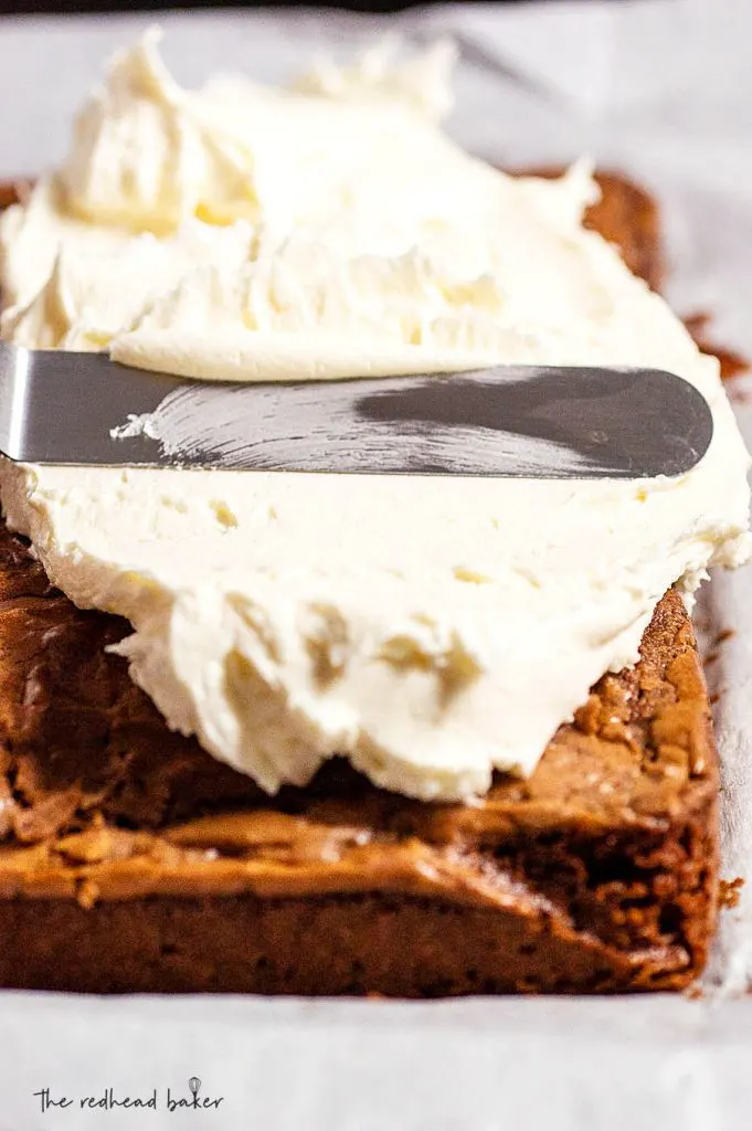 Frosting being spread onto a sheet of brownies