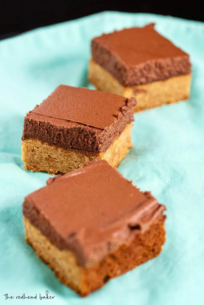 Three frosted peanut butter bars on a blue napkin