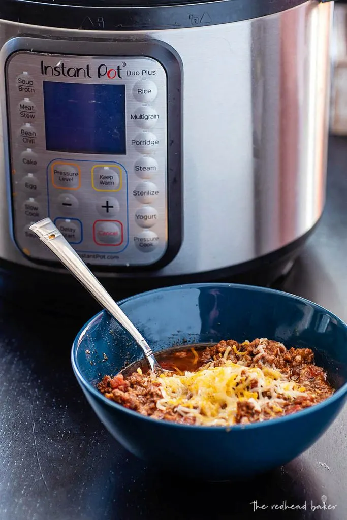 A bowl of beef chili in front of an Instant Pot