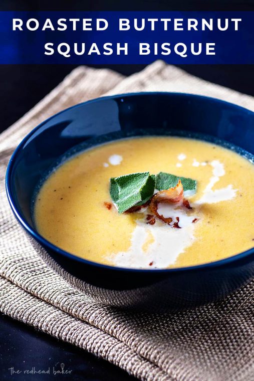 Roasted butternut squash bisque in a blue bowl garnished with sage and bacon