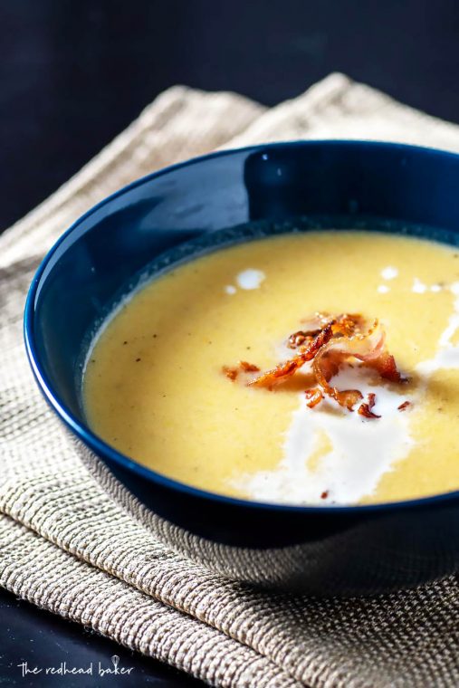 Roasted butternut squash bisque in a blue bowl garnished with bacon