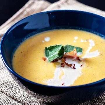 Roasted Butternut Squash Bisque is a smooth and creamy soup flavored with squash, apples, and herbs. A crispy bacon garnish gives contrasting texture.