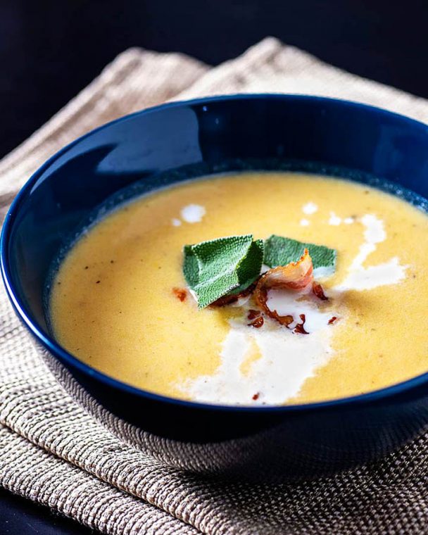 Roasted Butternut Squash Bisque is a smooth and creamy soup flavored with squash, apples, and herbs. A crispy bacon garnish gives contrasting texture.