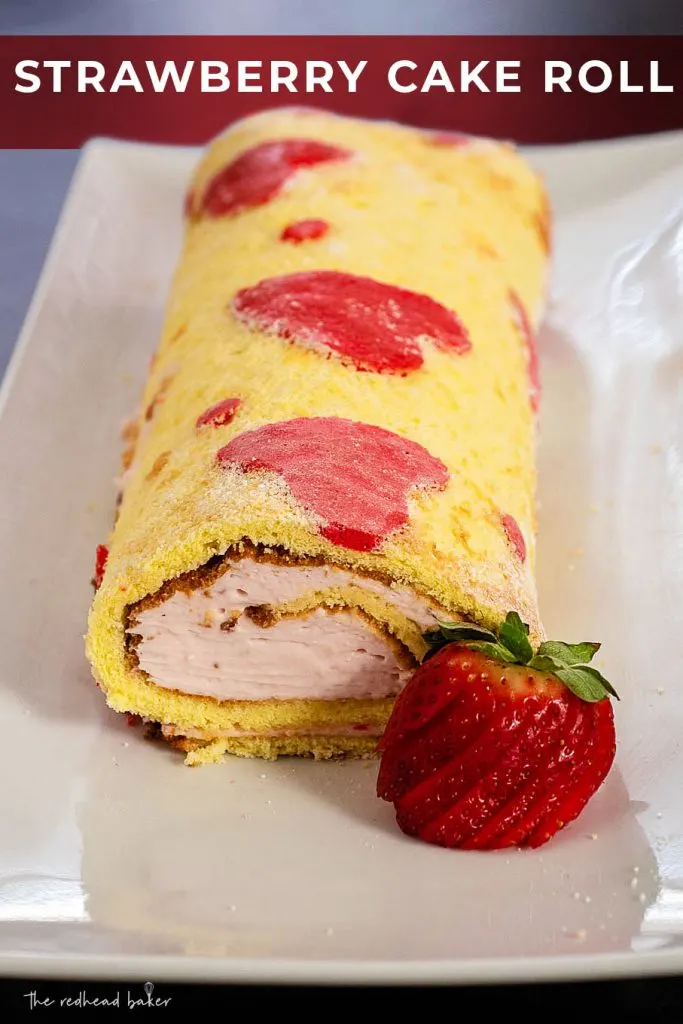 An overhead view of a strawberry cake roll, garnished with a fresh strawberry