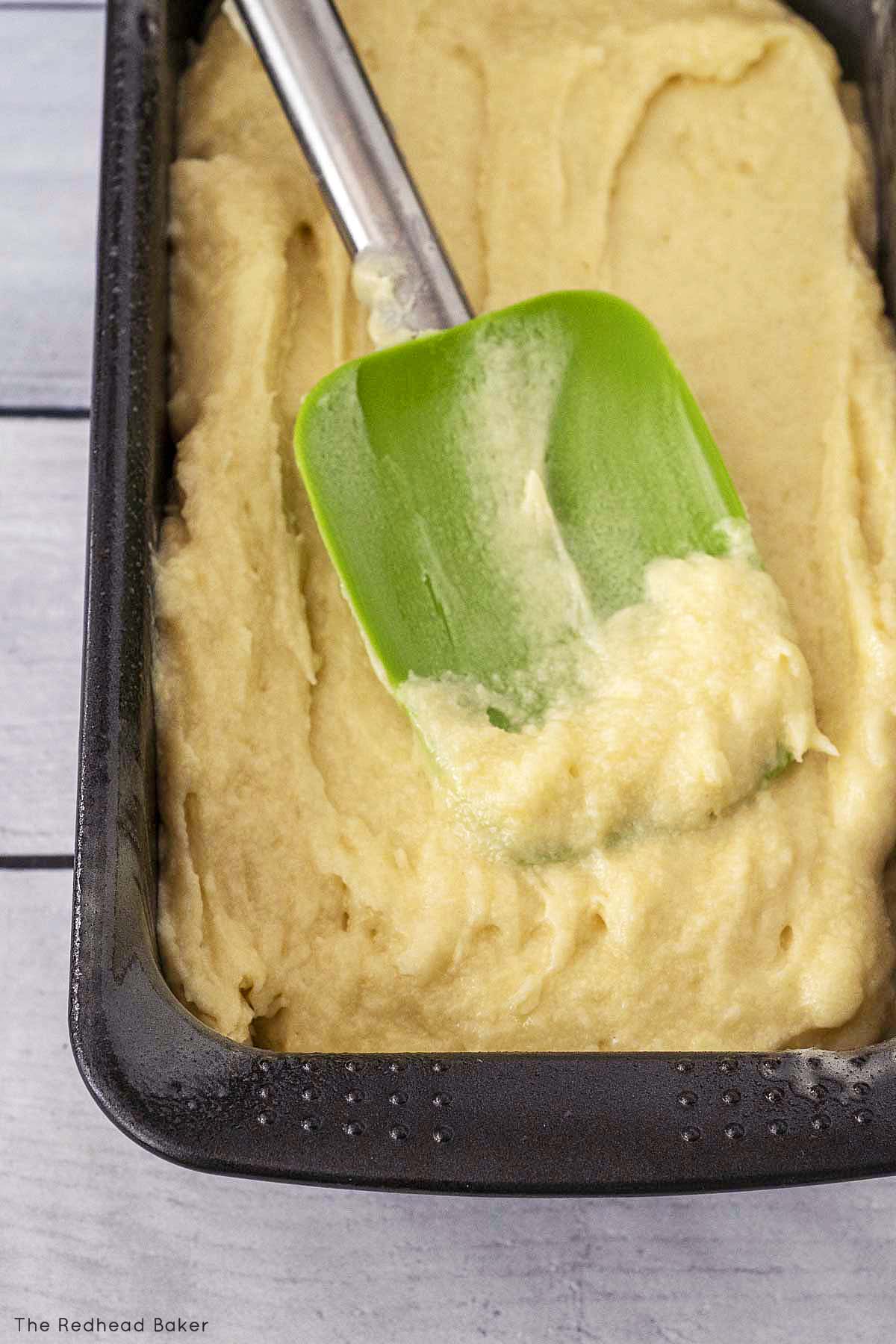 Pound cake batter being spread in a loaf pan.