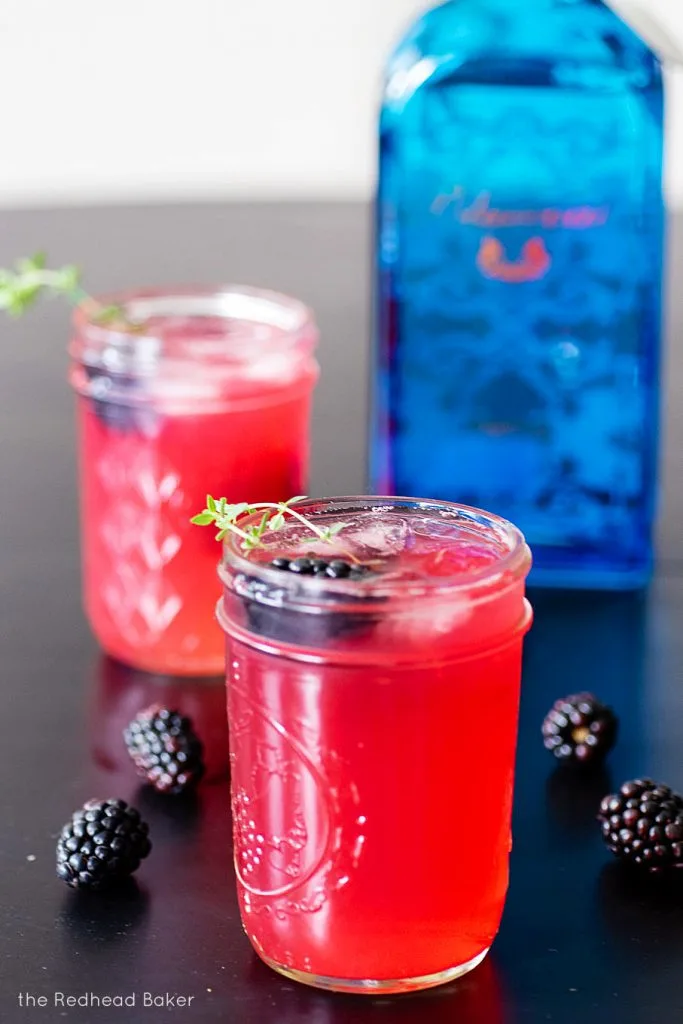 Two glasses of blackberry collins garnished with blackberries