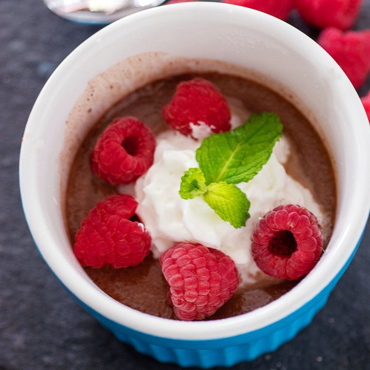 A ramekin of Instant Pot chocolate custard topped with whipped cream, fresh raspberries and a sprig of mint