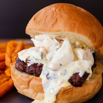 A close-up of a Neptune burger with Bearnaise sauce dripping down the side