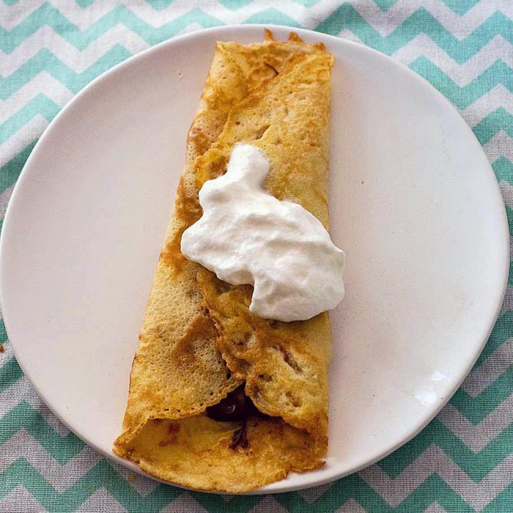 A filled rolled crepe topped with whipped cream