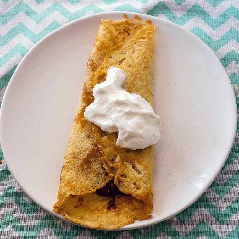 A filled rolled crepe topped with whipped cream