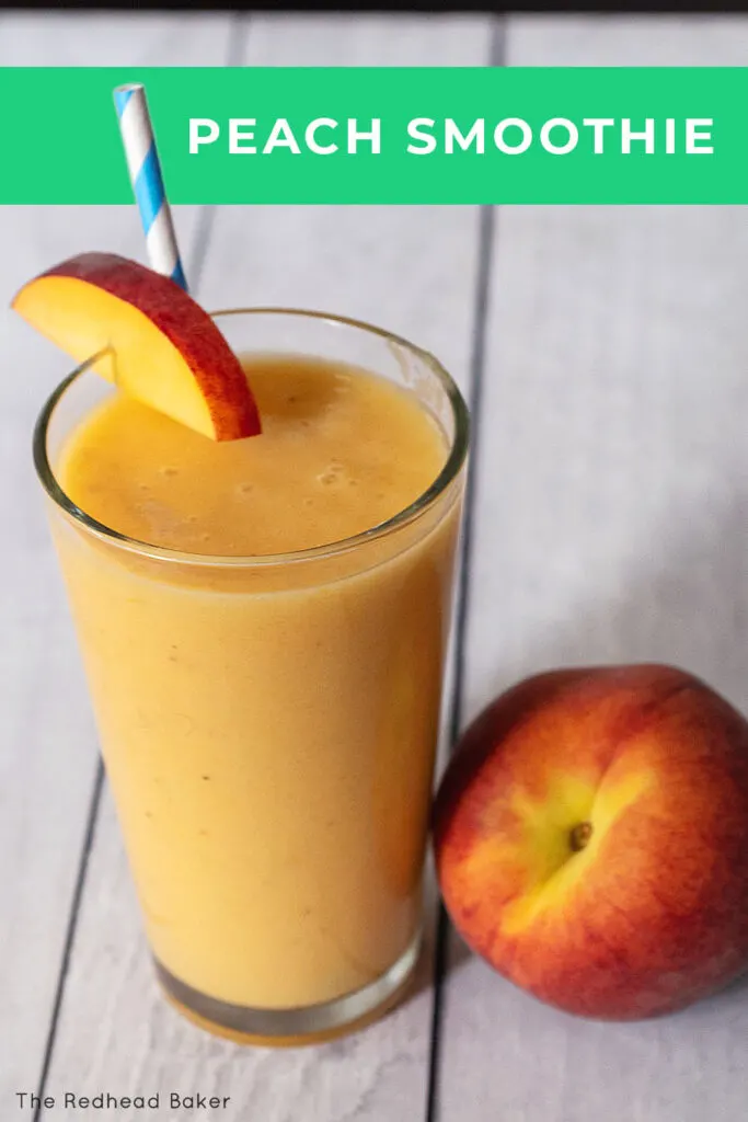 A glass of fresh peach smoothie next to a fresh peach