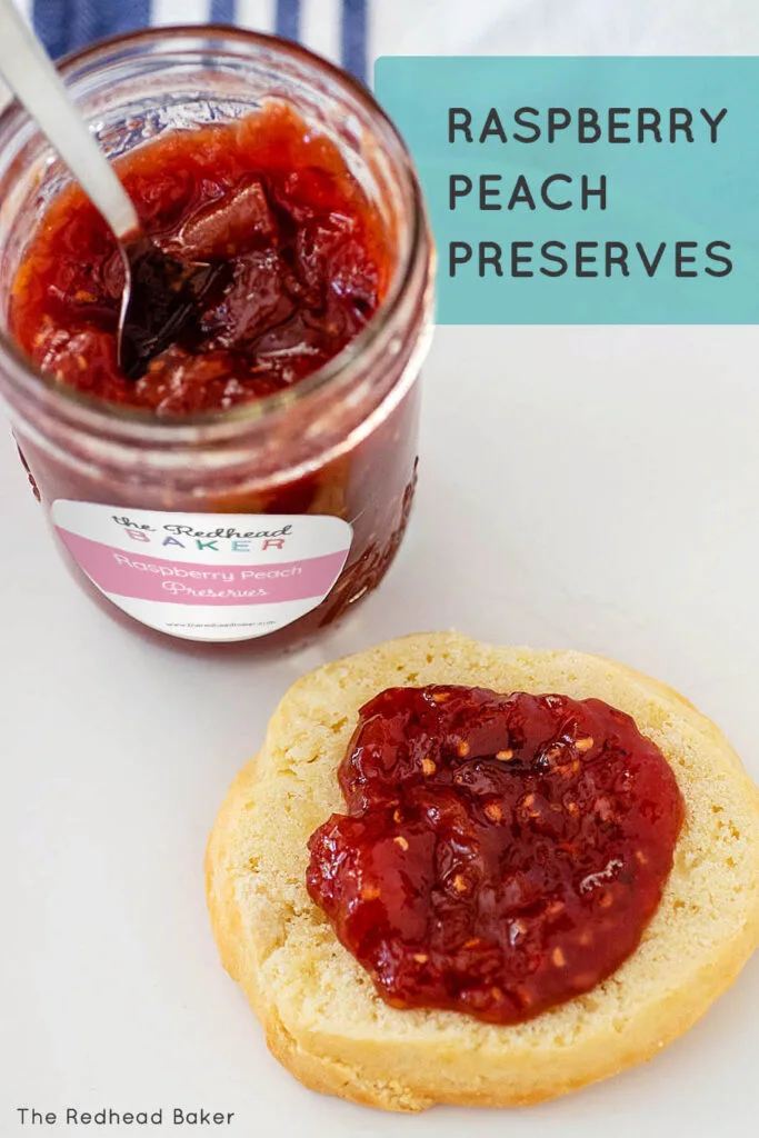 Half a shortcake spread with jam in front of an open jar