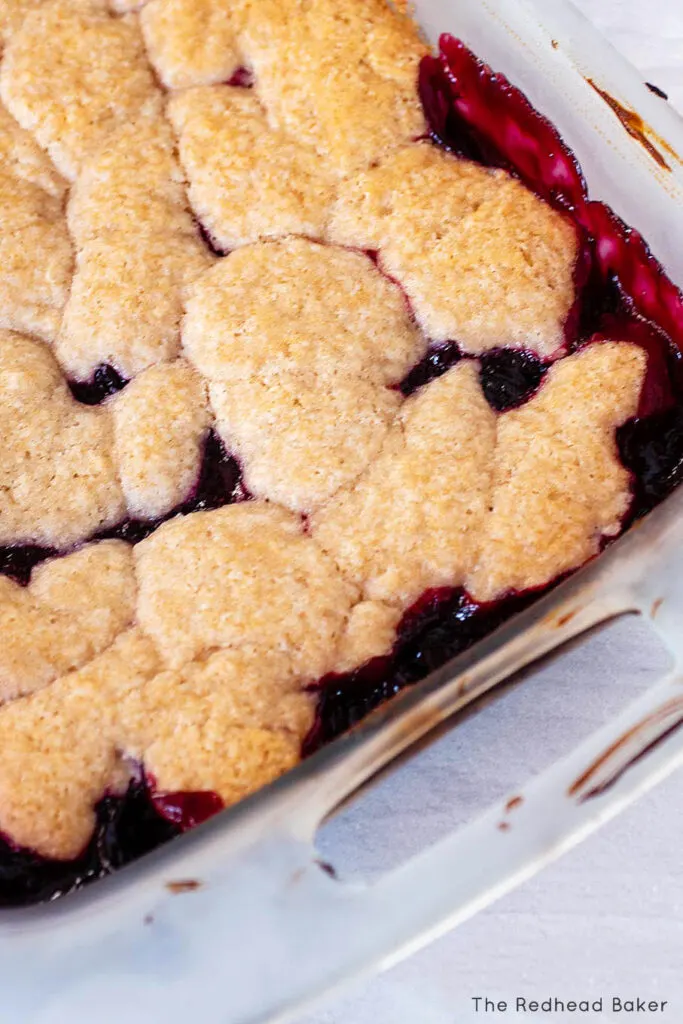 A close-up of baked cherry cobbler in its glass baking dish