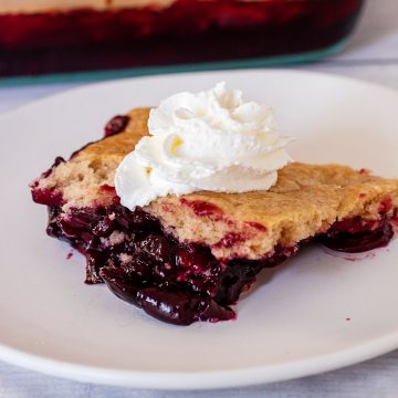 A portion of cherry cobbler topped with whipped cream