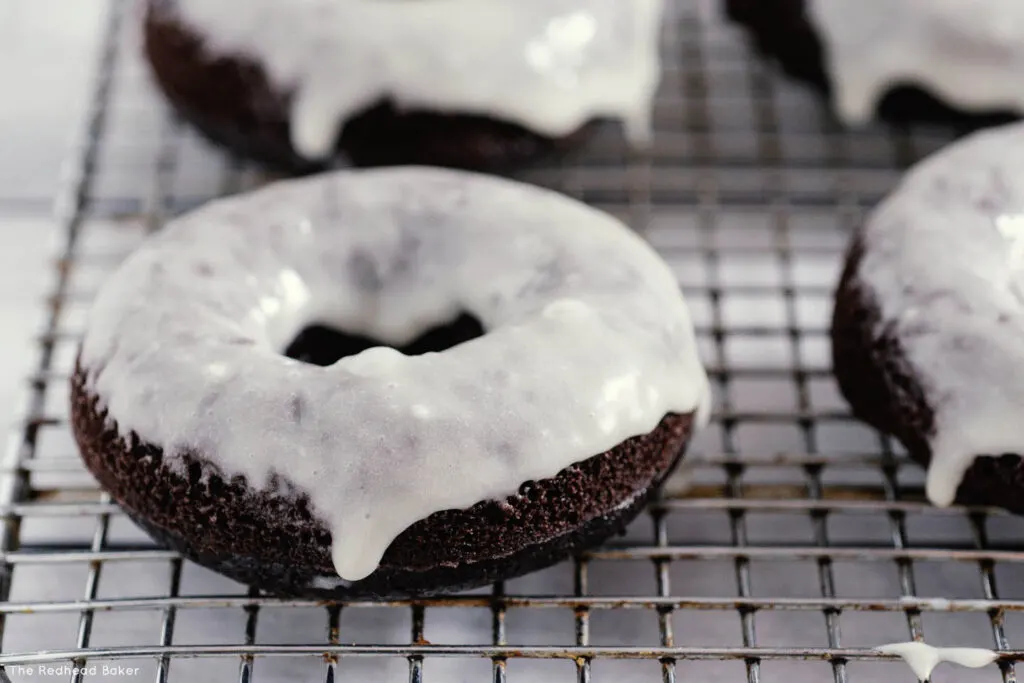 A baked glazed chocolate donut on a wire rack