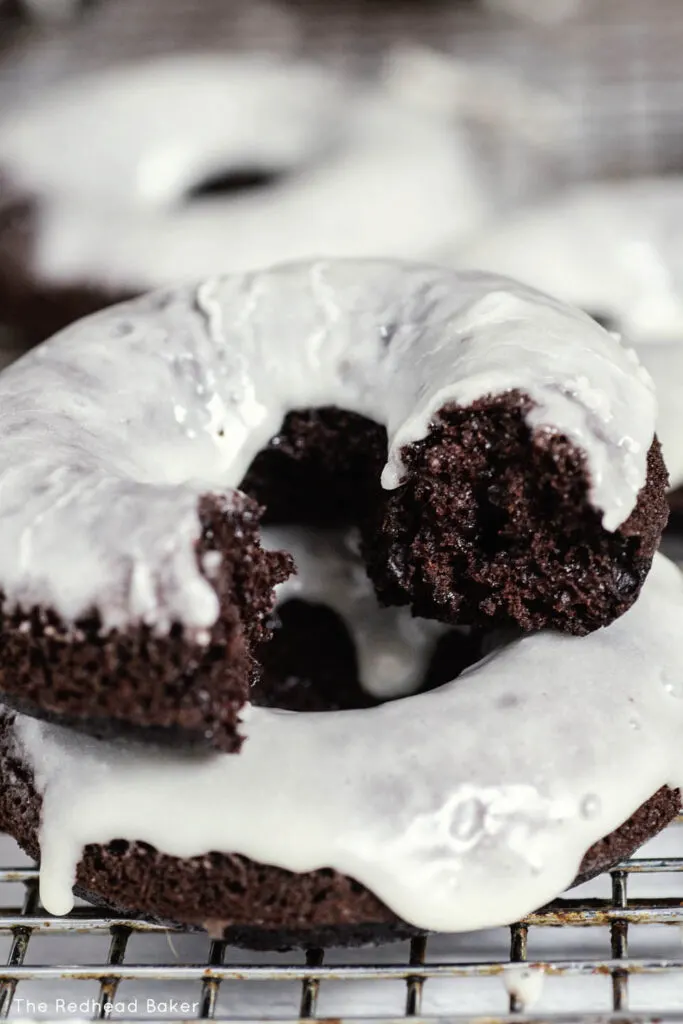 A close-up of a baked chocolate donut with a bite taken out