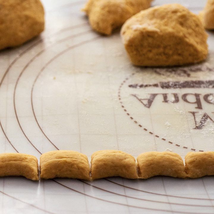 A rope of pumpkin gnocchi dough cut into 1-inch sections