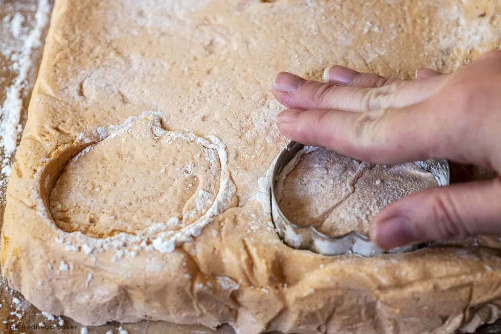 Cutting a sheet of marshmallow with a pumpkin-shaped cookie cutter