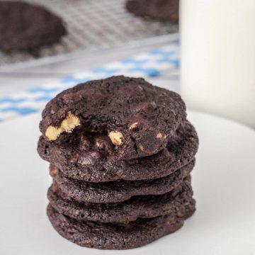 A stack of five chocolate peanut butter cookies with a bottle of milk