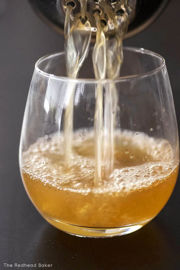 Cider whiskey sour being poured into a cocktail glass