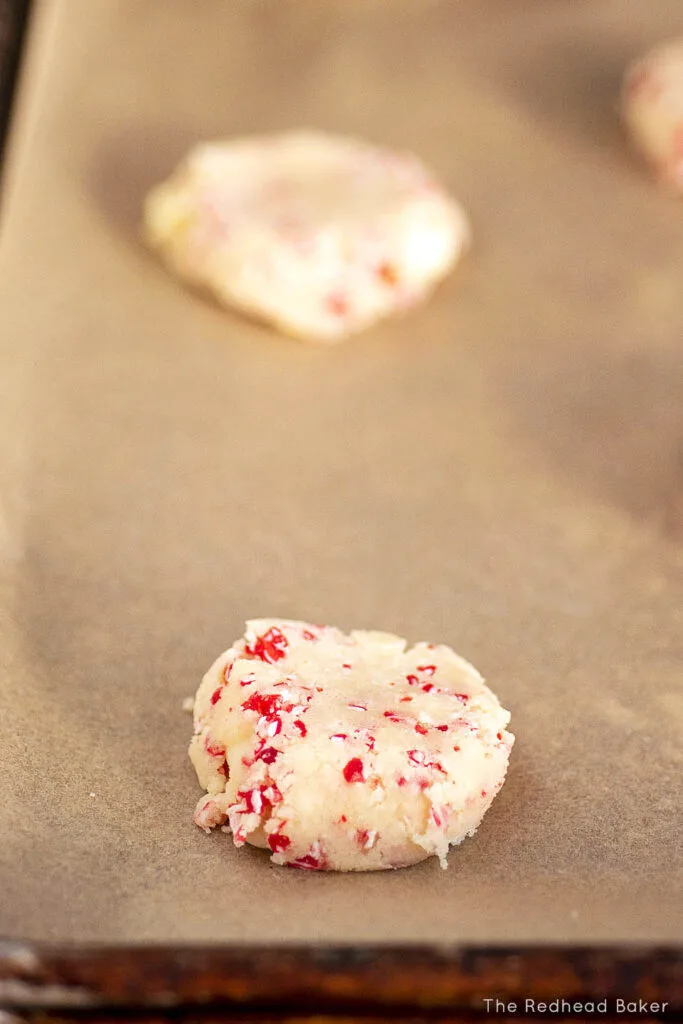 An unbaked ball of cookie dough on a parchment lined baking sheet