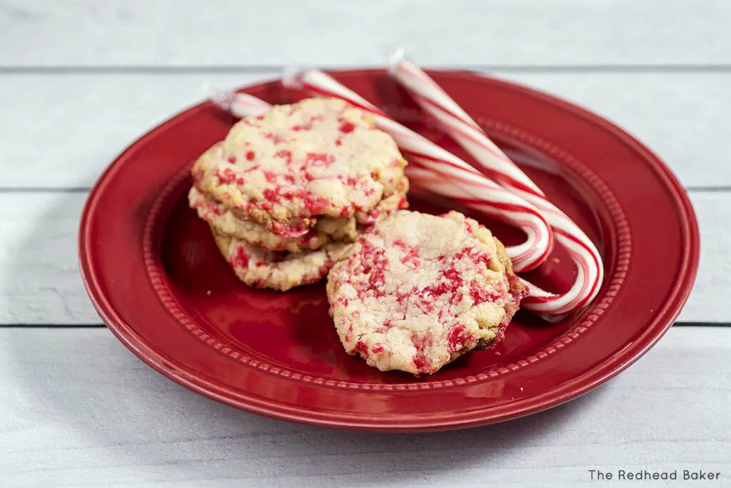 Three candy cane white chocolate cookies on a red plate