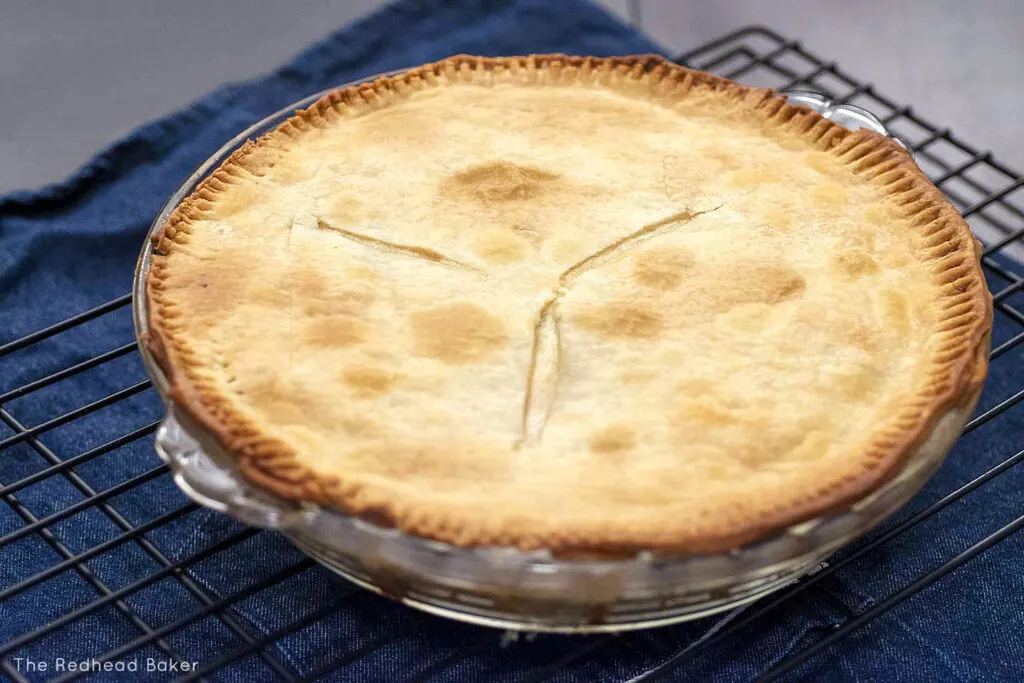 A whole, baked chicken pot pie on a cooling rack