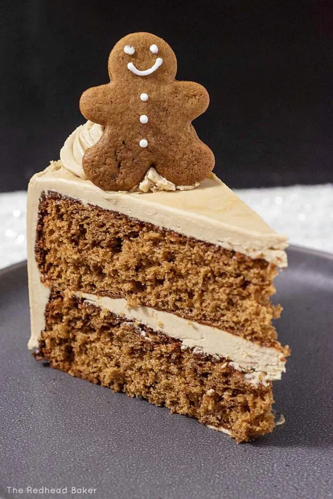 A gingerbread man on top of a slice of cake on a gray plate