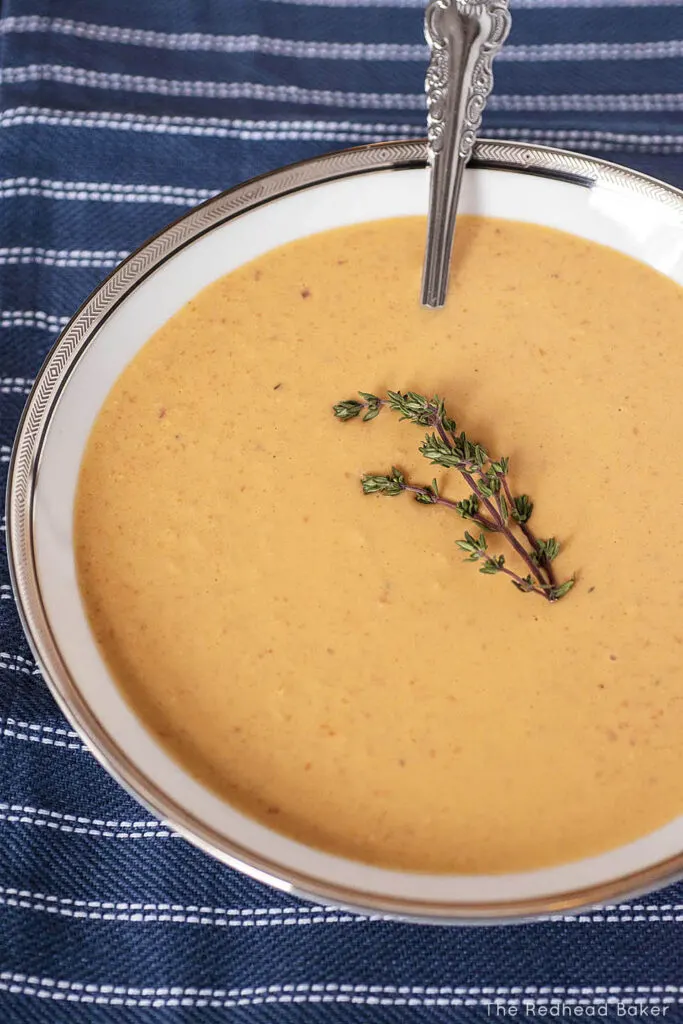 A high-angle view of a white bowl of bisque on a blue and white placemat