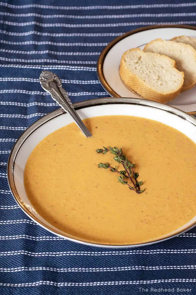 A soup bowl of lobster bisque in front of a plate of baguette slices