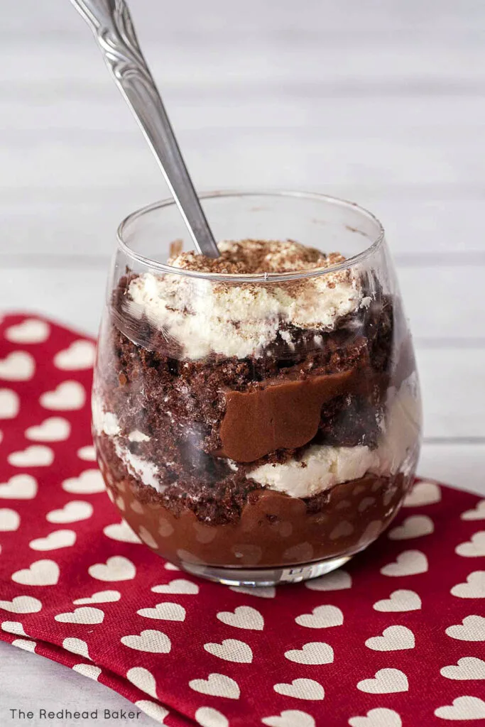 A single glass of triple chocolate trifle on a red tea towel