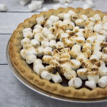 A pie plate of s'mores pie topped with toasted marshmallows