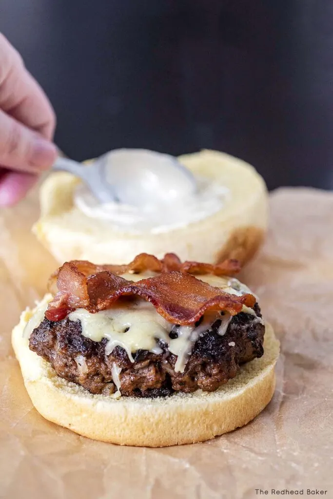 Whiskey aioli being spread on a burger bun