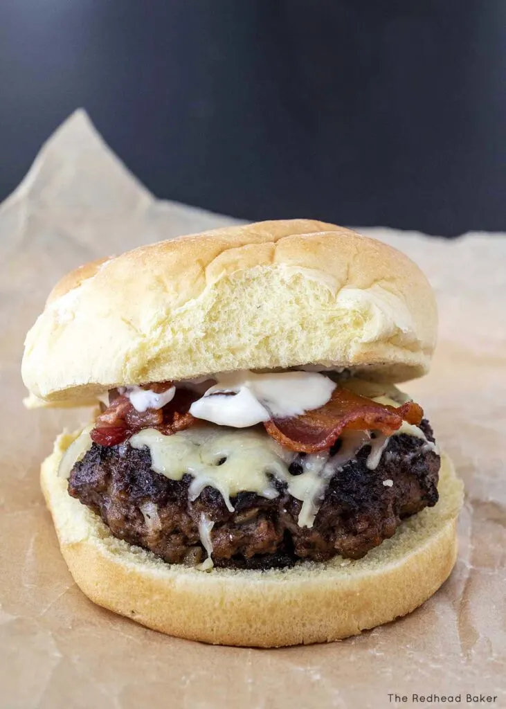 An Irish burger with cheddar, bacon, and whiskey aioli on a piece of parchment paper