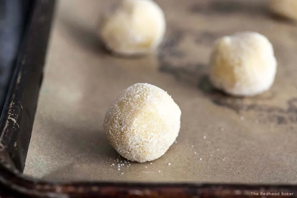 Three balls of lemon doodle dough on a baking sheet