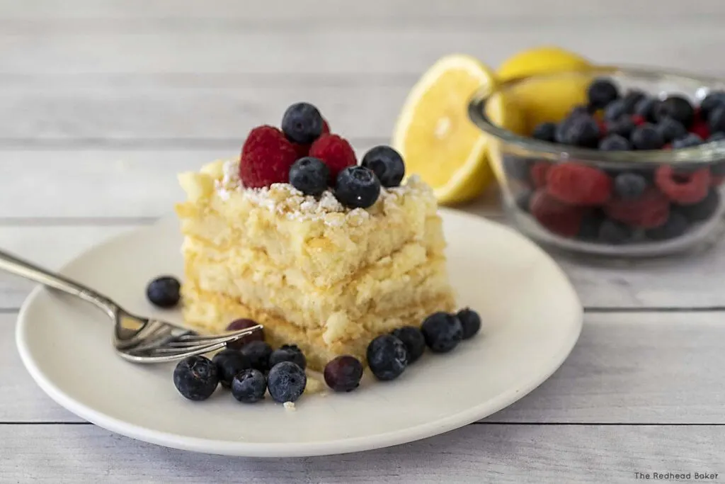 A slice of lemoncello tiramisu garnished with raspberries and blueberries