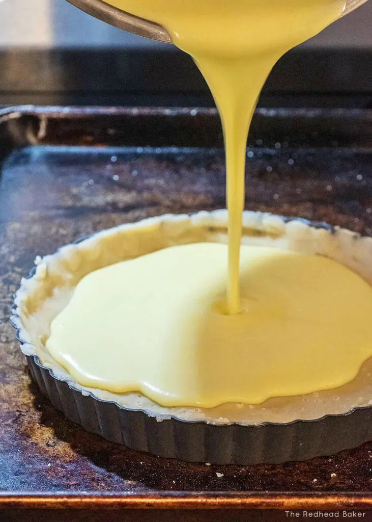 Lemon filling being poured into a shortbread crust