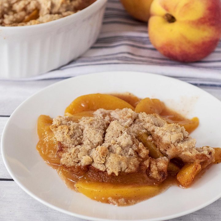 A plate of peach cobbler with cinnamon biscuit topping.
