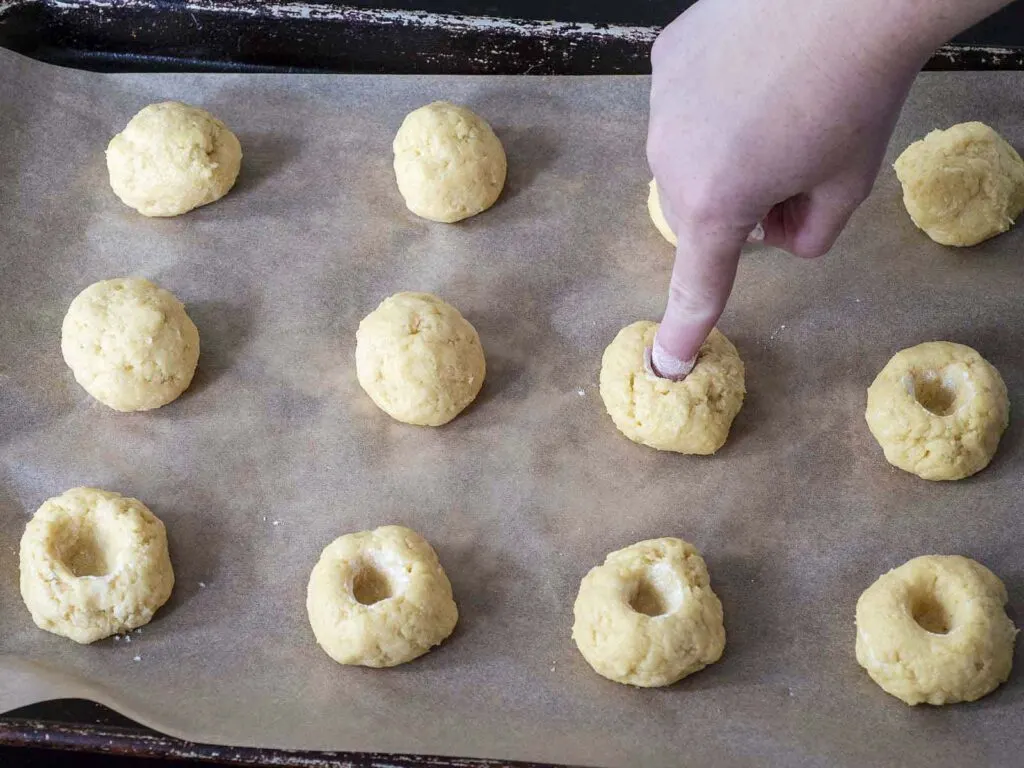 A finger poking a hole in one of the dough balls.