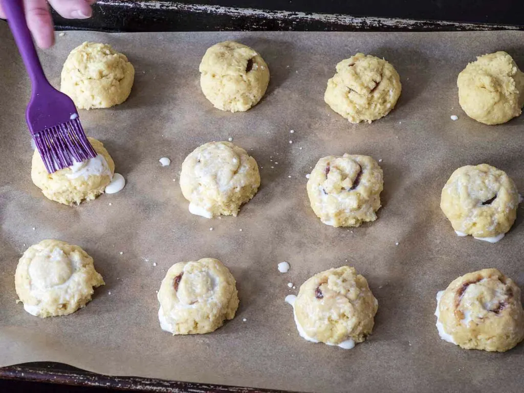 Brushing cream onto each ball of dough.