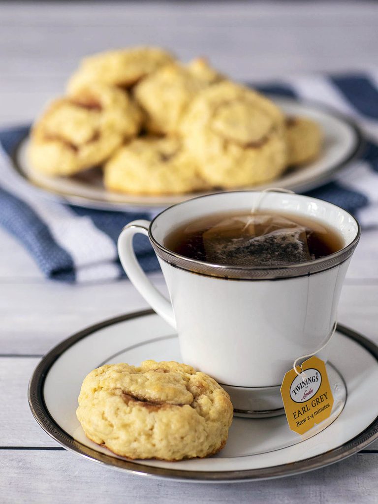 A cup of tea and a tea bun on a saucer