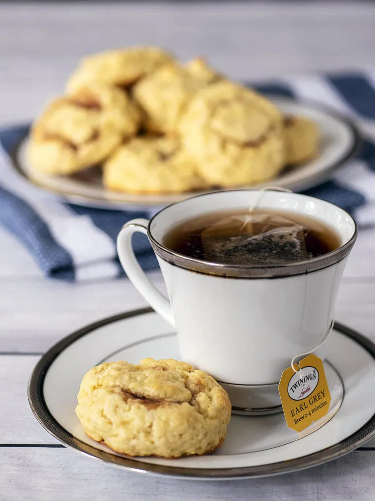 A cup of tea and a tea bun on a saucer