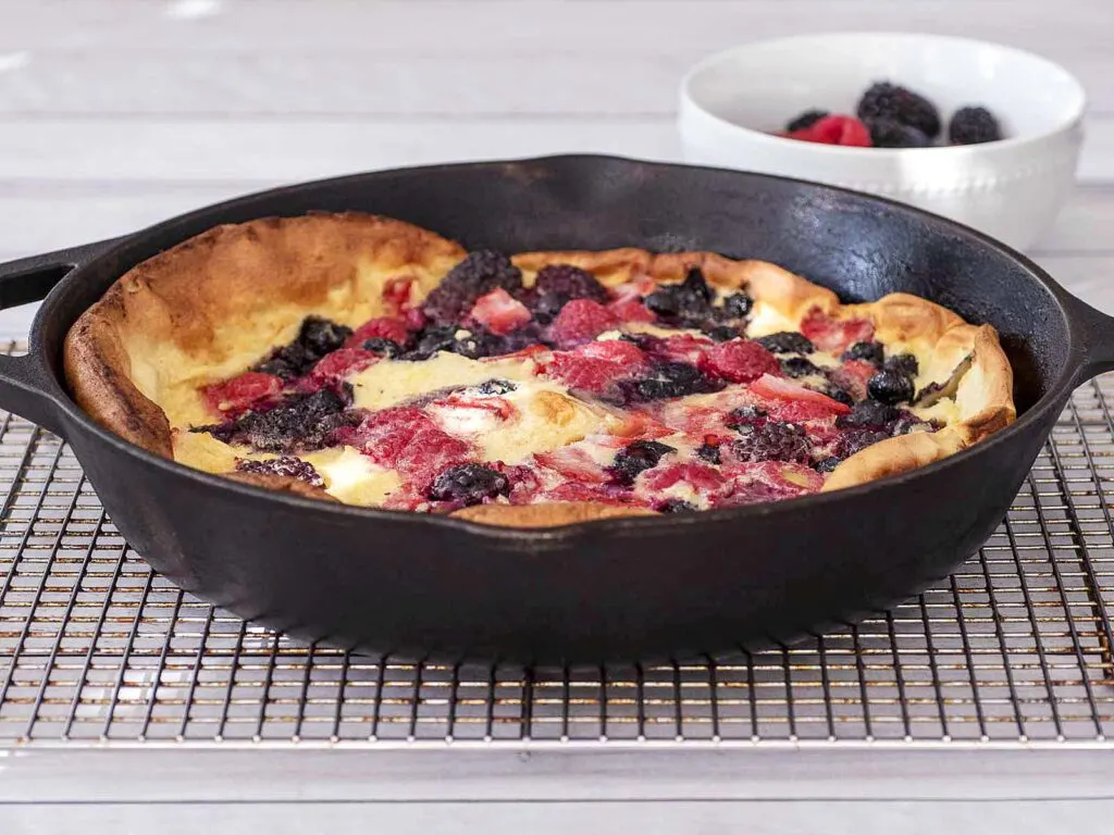 A cast-iron skillet with a baked berry Dutch baby.
