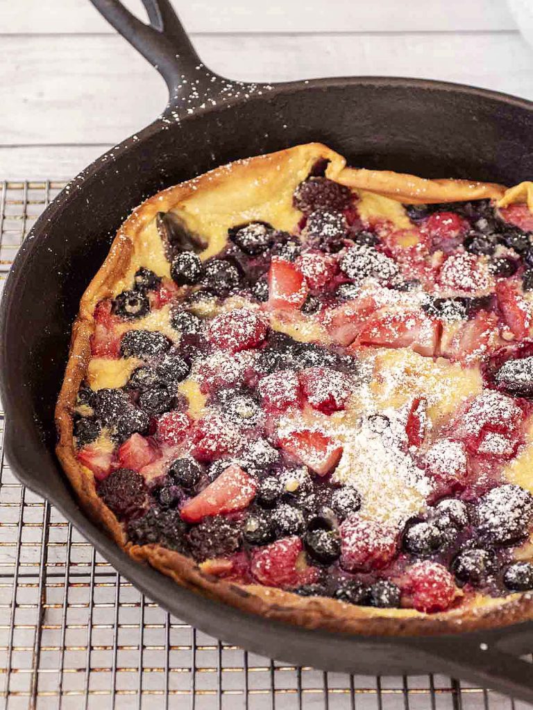 A Dutch baby in a cast-iron skillet dusted with powdered sugar.