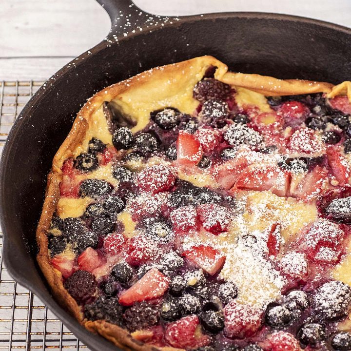 A dutch baby with berries in a cast-iron skillet.