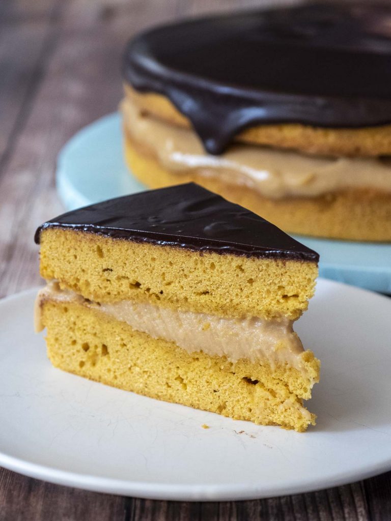 A slice of Pumpkin Boston Cream Pie in front of the rest of the cake.