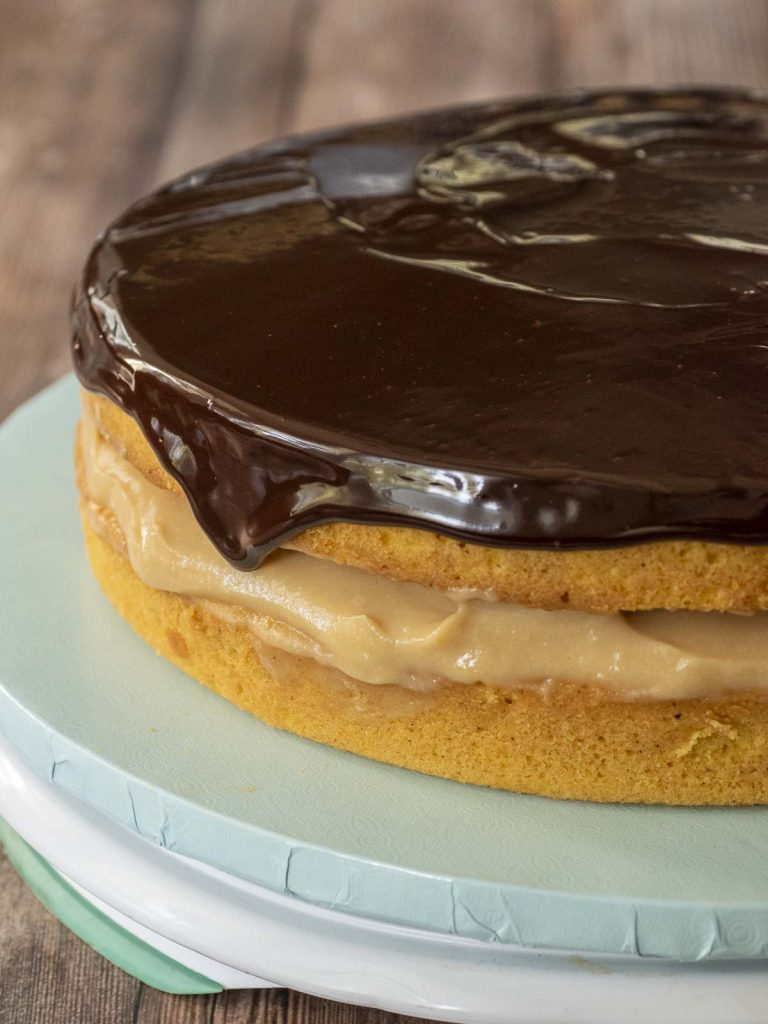 A whole Boston cream pie with chocolate glaze dripping down the side.