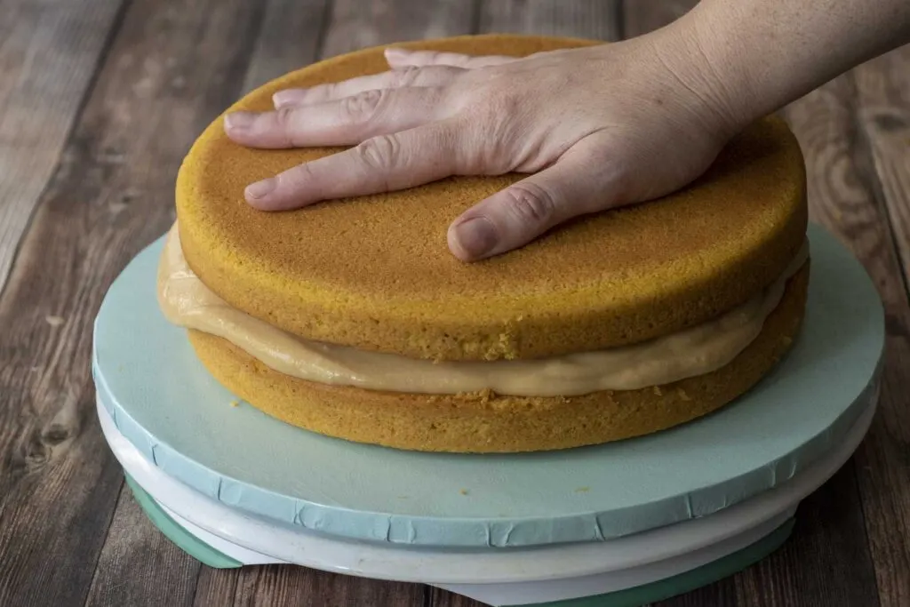 Placing the second layer of pumpkin sponge cake.